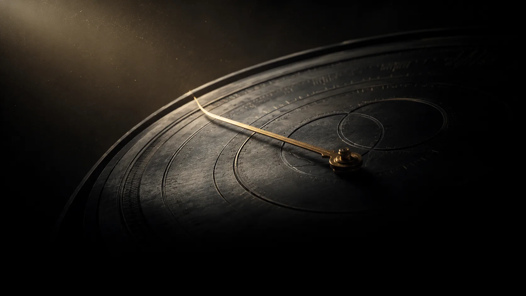 A dark precision instrument dial with a single gold indicator needle, lit by one beam of light